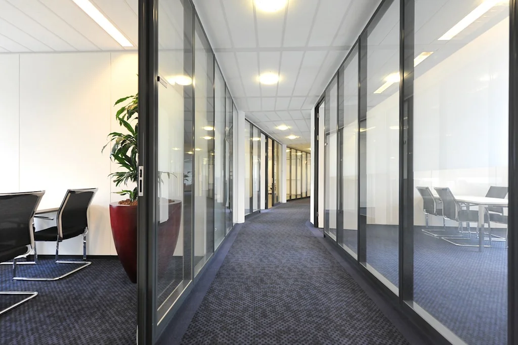 Gang in een modern kantoorpand aan de Laan van s-Gravenmade met glazen kantoorwanden en vergaderruimtes.